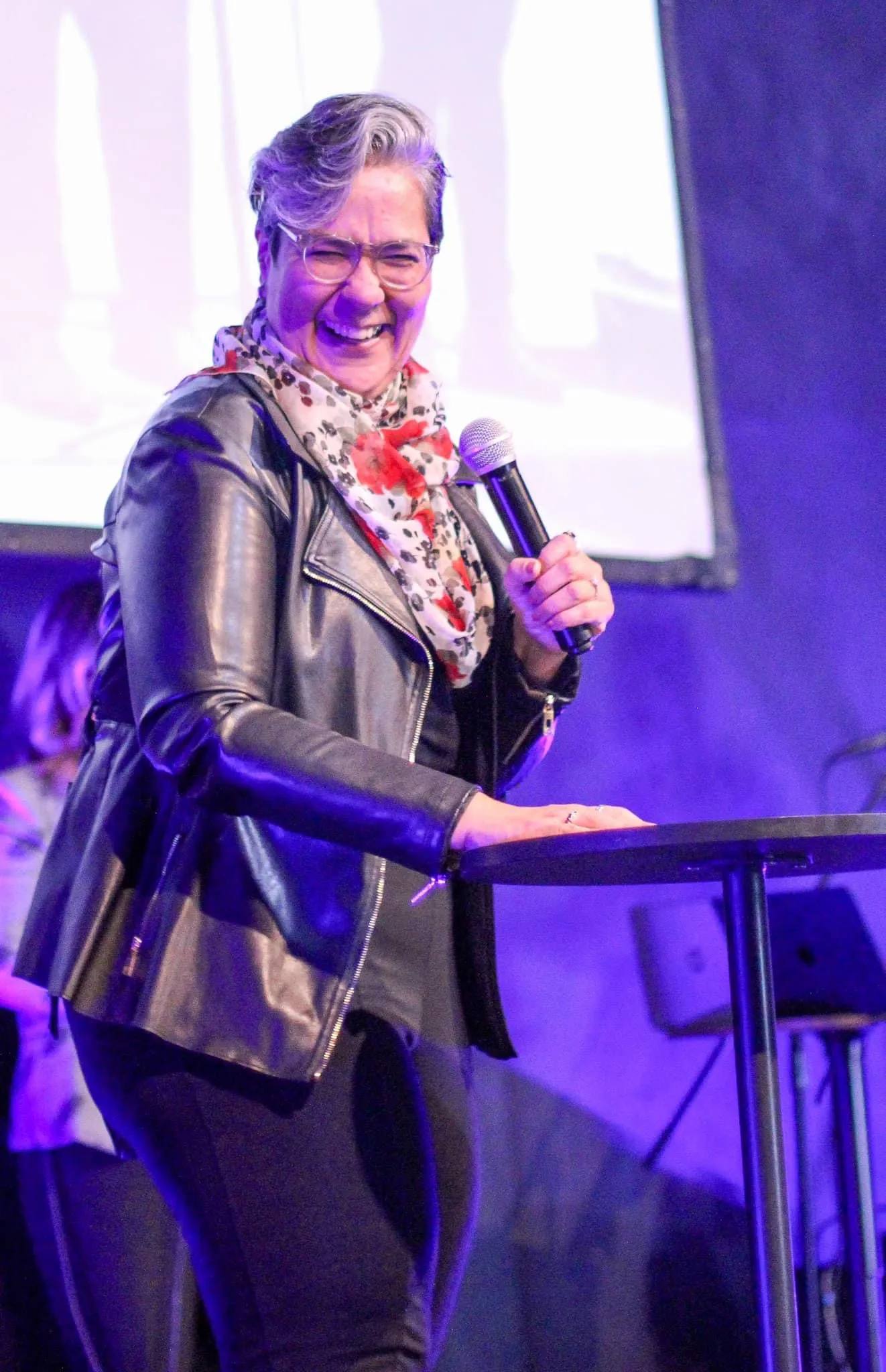 Lili García sonriendo con un micrófono durante una conferencia